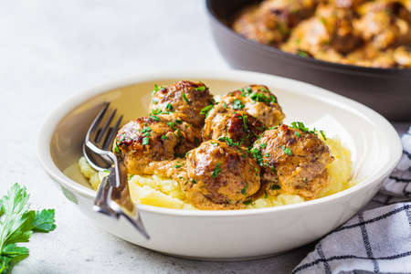Swedish meatballs in a creamy sauce with mashed potatoes in a white plate, gray background. Scandinavian food concept.の写真素材