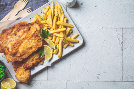 Fish and chips with green peas on a gray tile background, top view, copy space. British cuisine concept.の写真素材