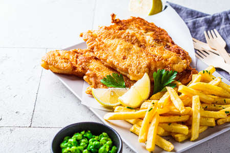 Fish and chips with green peas on a gray tile background. British cuisine concept.の写真素材