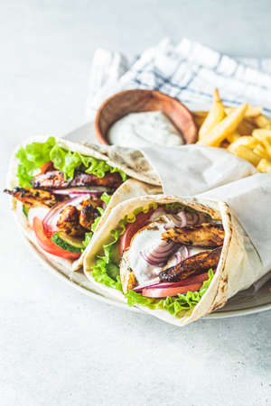 Chicken gyros with vegetables, french fries and tzatziki sauce on a plate. Greek food concept.の写真素材