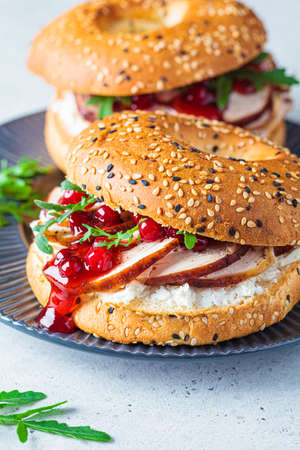 Thanksgiving food concept. Bagel sandwich with turkey and cranberry sauce on gray plate, close-up.の写真素材