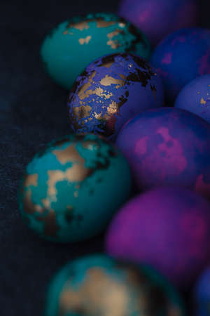 Easter eggs purple and blue with golds on dark background, close-up.