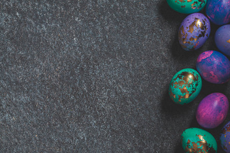 Easter eggs purple and blue with golds on a dark background, copy space.