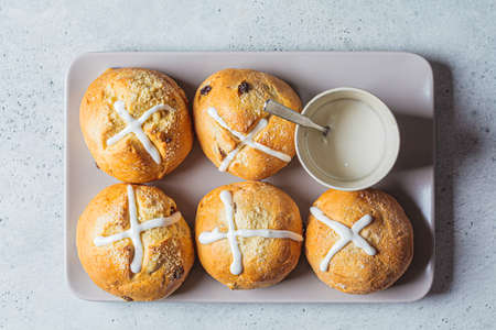 Traditional Easter cross buns with raisins on gray plate, top view.