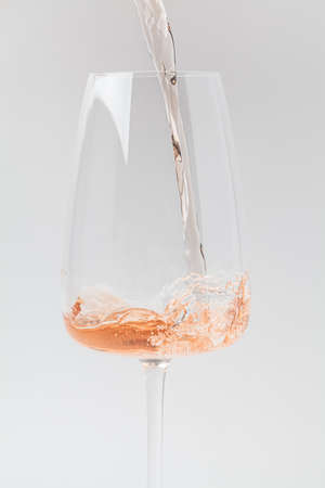 Rose wine is pouring into a crystal glass, close-up, vertical.の写真素材