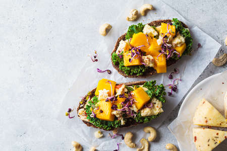 Vegan toasts with cashew cheese, mango and kale, top view, copy space. Alternative plant-based food,...