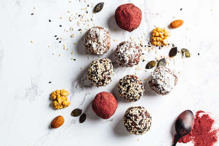 Raw vegan dessert. Energy balls. Truffles made from nuts, seeds, cocoa, dates and various superfood powders, flat lay, white marble background.の写真素材