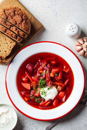 Beetroot soup borsch with garlic, sour cream and dill in plate, top view. Russian or Ukrainian...