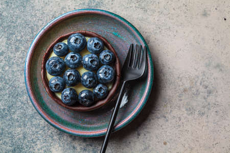 Tartlet with blueberries, chocolate and cream cheese, top view, copy space. Vegan dessert concept.の写真素材