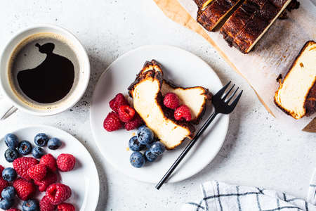 Flat lay of homemade San Sebastian burnt cheesecake with berries on white plate for breakfast, top...