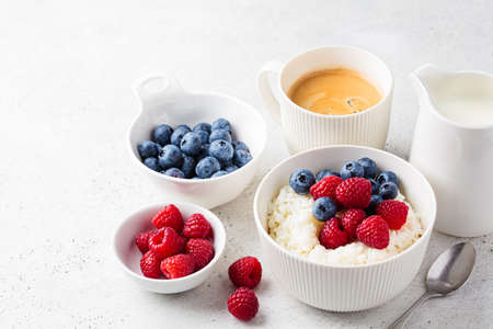 Rice pudding with berries and butter. Porridge bowl with raspberries and blueberries. Healthy summer breakfast recipe.の写真素材