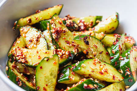 Chinese smashed cucumber salad with chili peppers and sesame seeds, close-up.