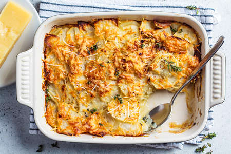 Baked potato gratin with cheese and thyme in oven dish, gray background, close-up, top view.の写真素材