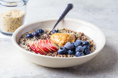 Quinoa porridge with apple, blueberry, peanut butter and hemp seeds in almond milk for breakfast....