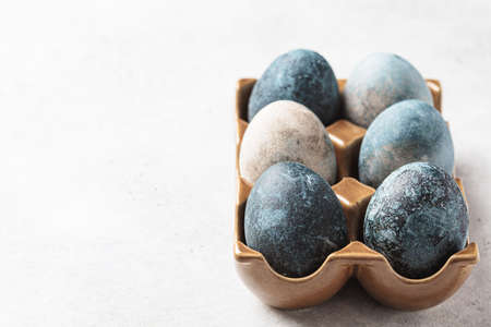 Easter eggs painted in trendy denim blue in a brown stand, copy space, gray background.の写真素材