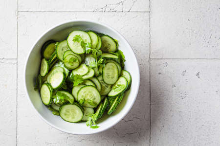 Fresh cucumber salad with cilantro and oil in a white bowl, top view.の写真素材