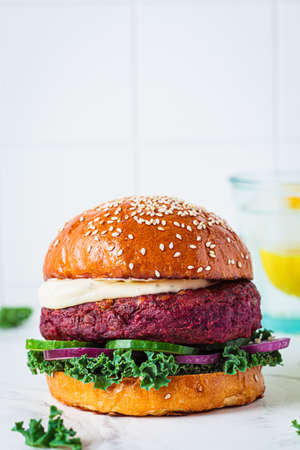 Beetroot vegan burger with kale, onion and cucumber, light background. alternative fast food. Purple food.の写真素材