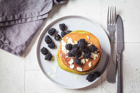 Vegan green matcha pancakes with blackberries, syrup and almonds, top view. Plant-based recipe, healthy breakfast, alternative food concept.の写真素材