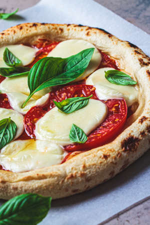 Vegan neopolitan margherita pizza with tomatoes, plant-based mozzarella and basil on a dark...