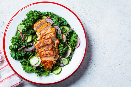 Grilled chicken breast salad with kale, cucumber, radish and onion, top view, copy space. Healthy protein food, low carb diet.の写真素材