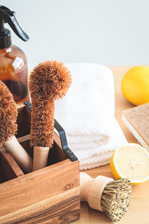 Zero waste eco friendly products and tools for kitchen cleaning. Wooden brushes, coconut sponges, spray vinegar, lemon and organic soap, gray background.の写真素材
