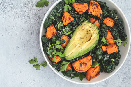 Roasted sweet potato, avocado, kale salad in white bowl. Alternative, healthy, based-plant recipe.