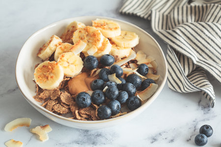Multigrain wholewheat breakfast cereals with banana, coconut and blueberries. Vegan breakfast concept.の写真素材