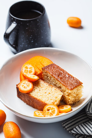 Kumquat pound cake pieces and a cup of coffee, white background.の写真素材