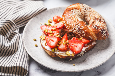 Sweet bagel with cream cheese, strawberries and pistachio for breakfast.の写真素材
