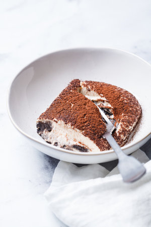 Portion of homemade tiramisu with chocolate cookies in bowl.