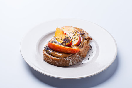 Peanut butter toast with peach and seeds. Vegan healthy snack concept.の写真素材