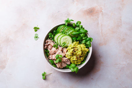 Asian salad bowl with tuna, avocado and cucumber. Pink marble background, top view.の写真素材