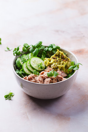 Asian salad bowl with tuna, avocado and cucumber. Pink marble background.の写真素材