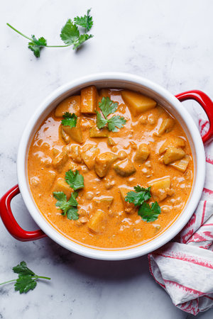 Vegan curry chickpea stew with vegetables in a red saucepan.の写真素材