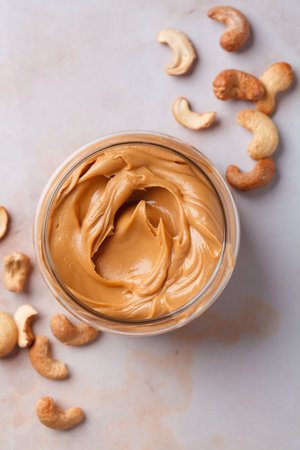 Cashew homemade nut butter in a glass jar, top view. Vegan healthy snack concept.の写真素材
