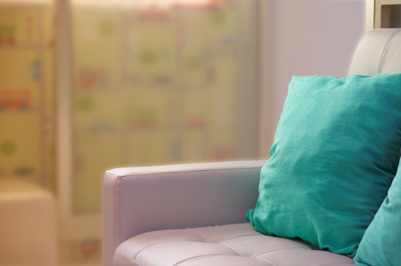 green pillows on white sofa beside glass door with sun lightの写真素材