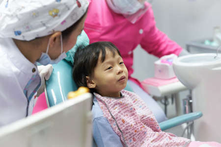 cute boy talking with dentist on chair and assistant before dental care check upの写真素材
