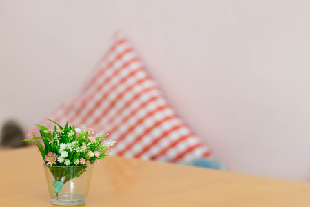 plastic flowers in glass vase on table with blur pillow backgrpoundの写真素材