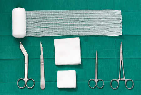 surgery tools ,scissors ,roll gauze,bandage,pad,cramp,blade,knife on green surgical dress background ,bird eye viewの写真素材