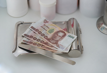 money backnote on medicine tray with spatula pill with drug plastic jar on background in payment healthcare hospital cost admit conceptの写真素材