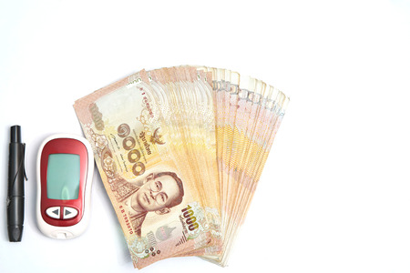 Money and lancet tool and blood sugar measure instrument on white background in diabetes control conceptの写真素材