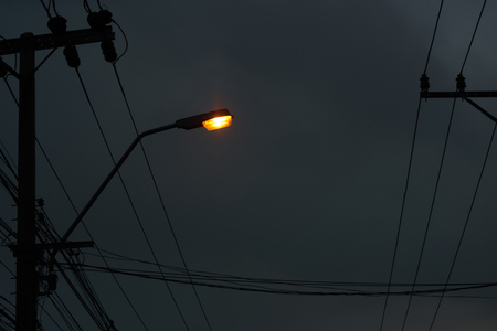 light lamp on pole with electric wires on dark night sky backgroundの写真素材