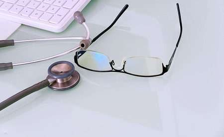 doctor desk with glasses,keyboard,mouse pad and stethoscope with copy test spaceの写真素材