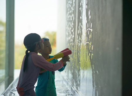 Kids play water gun to wallの写真素材