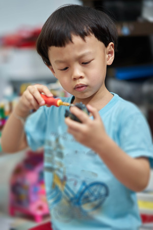 kid fixs toy with screw driverの写真素材