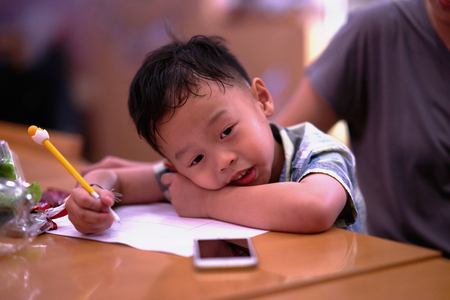 Boy is working on homework on table with Momの写真素材