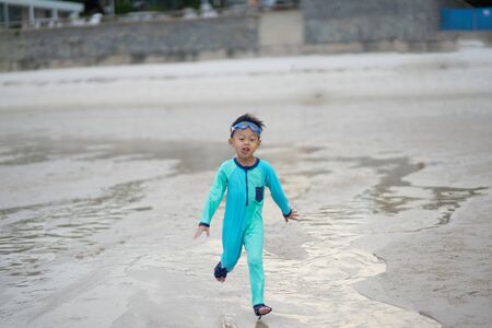 Kid in swimming suit run on the hotel beach front in motion blurの写真素材