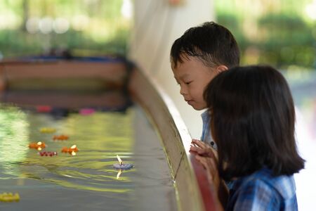 Boy and girl look at candle floater in water with happinessの写真素材