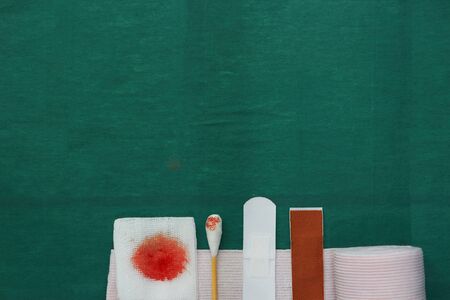 half tools includes plaster,swab,blood gauze and roll gauze on green surgical dress for clean wound...