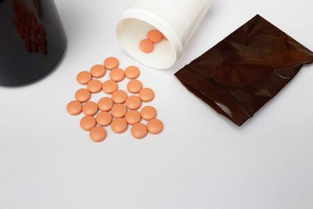 Orange coated round drug tablets on drugstore tray and bottle in business medical pharmaceutical...